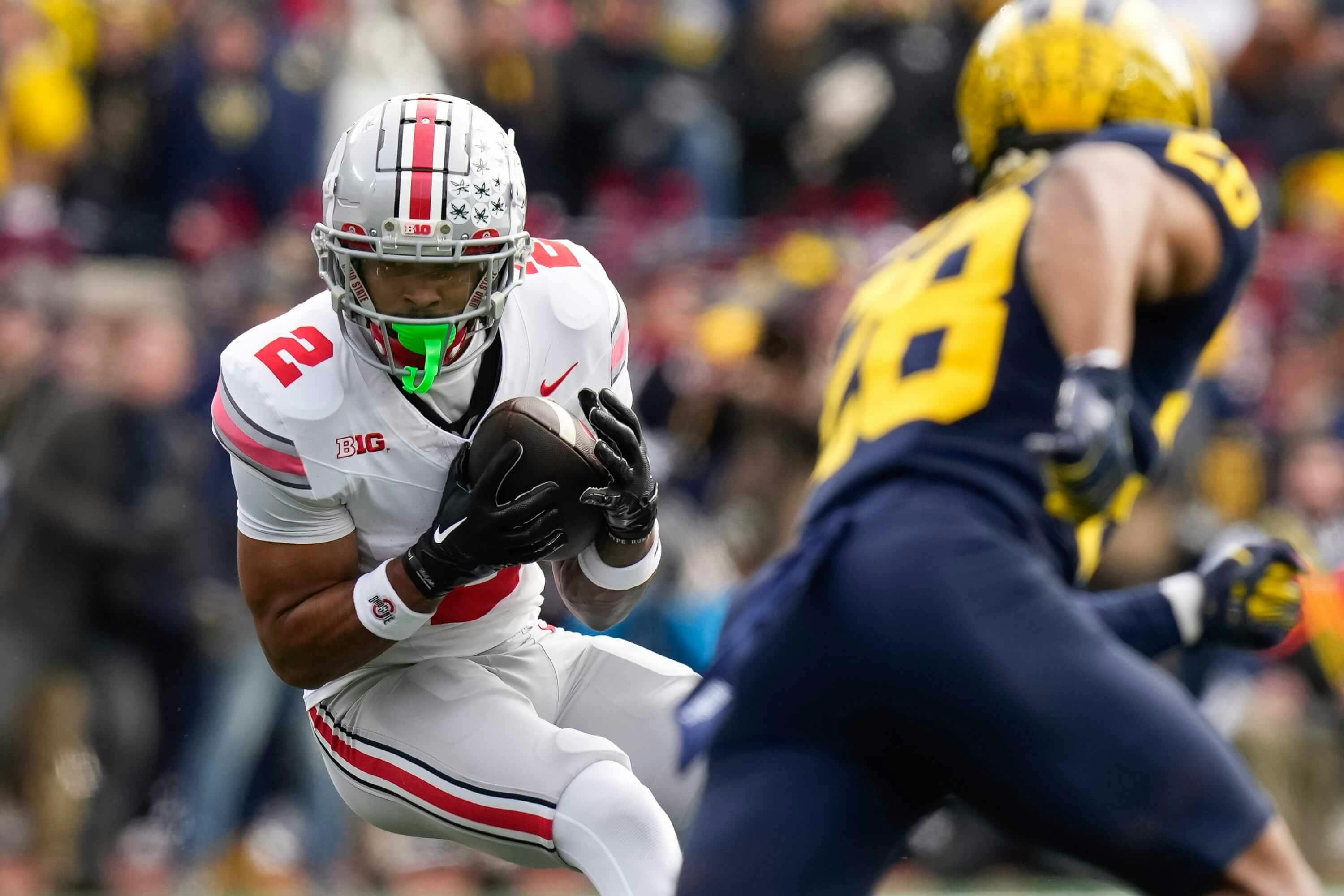 Ohio State Buckeyes wide receiver Emeka Egbuka (2) catches a pass in front of Michigan Wolverines defensive back Quinten Johnson (28) during the NCAA football game at Michigan Stadium. Ohio State lost 30-24.