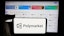 In this photo illustration, a person is holding a cellphone with the logo of crypto prediction market company Polymarket on screen in front of business webpage.