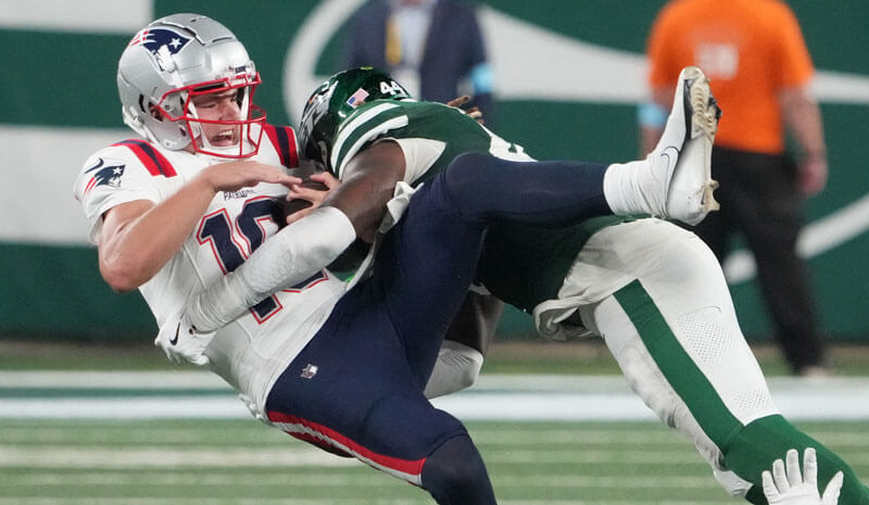 New England Patriots quarterback Drake Maye (10) gets sacked hard by a New York Jets linebacker as I drop my Jets vs. Patriots predictions.
