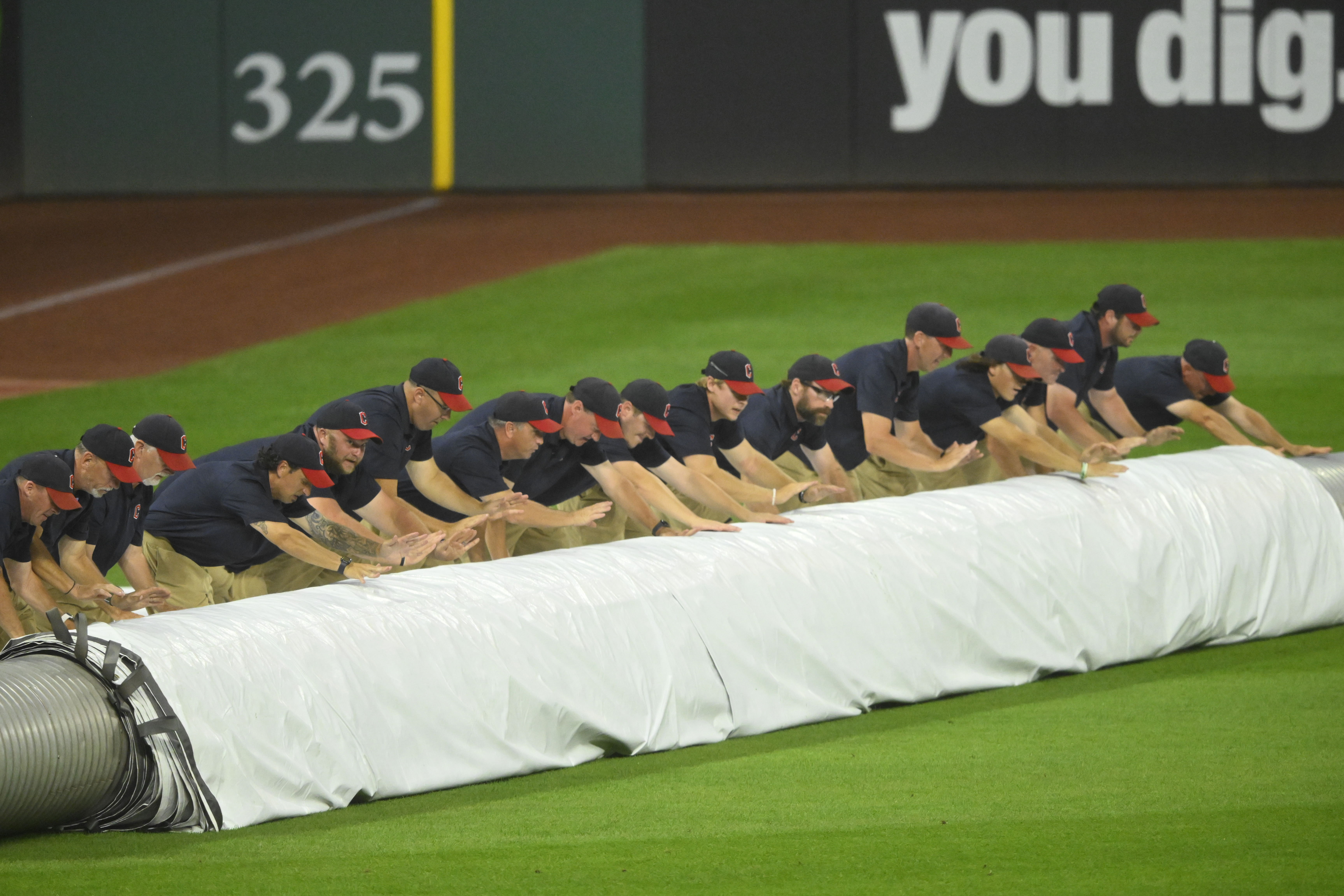 The Progressive Field grounds crew unrolls the tarp during a rain delay.