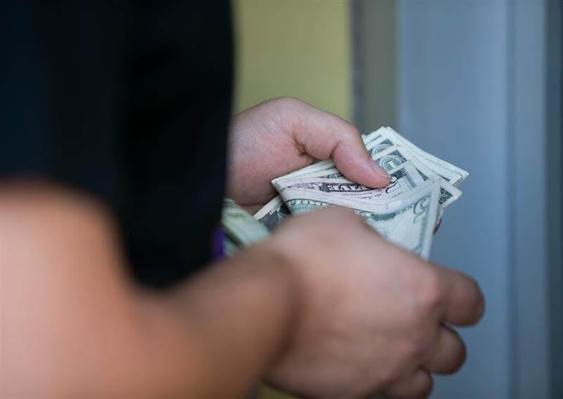 A man counts his money while placing a bet at the Caesars Sportsbook betting window at Chase Field in Phoenix on the first day of sports betting on September 9, 2021. 