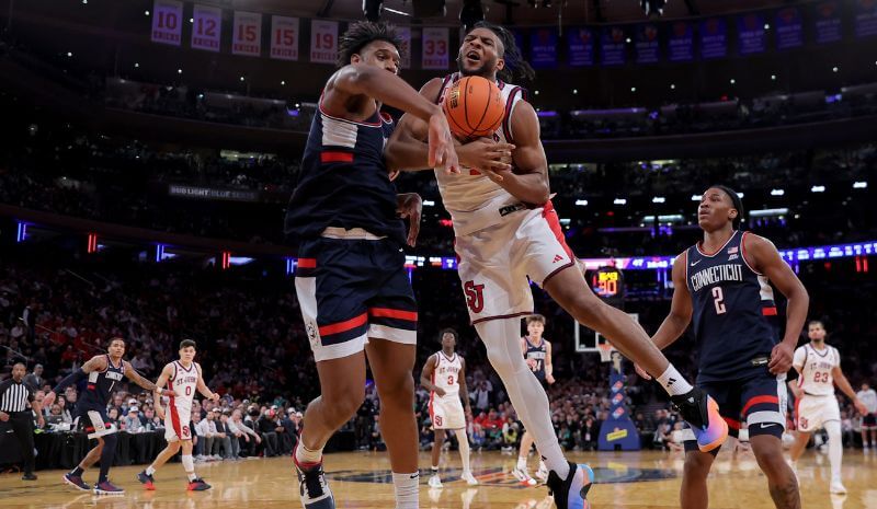 St. John’s player drives to the basket against Connecticut defenders during the Big East Tournament championship game.