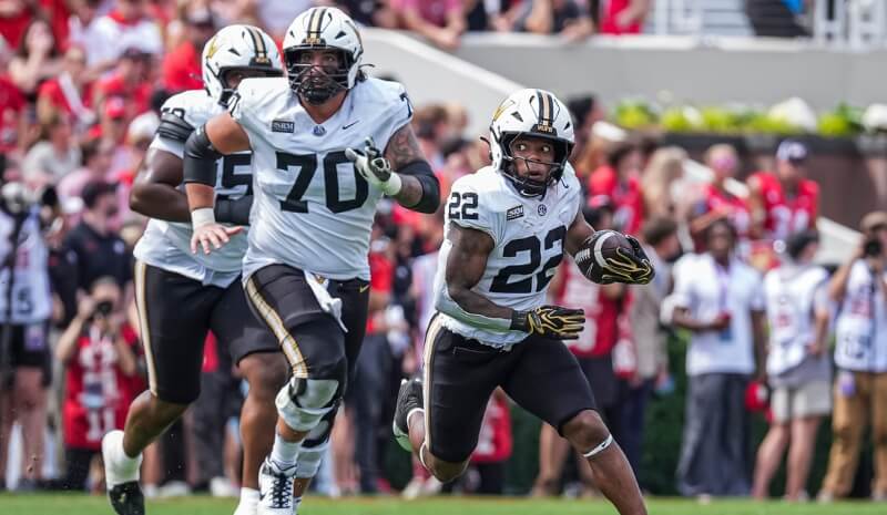 Vanderbilt Commodores running back Makhilyn Young (22) runs behind offensive lineman Cade McConnell (70).