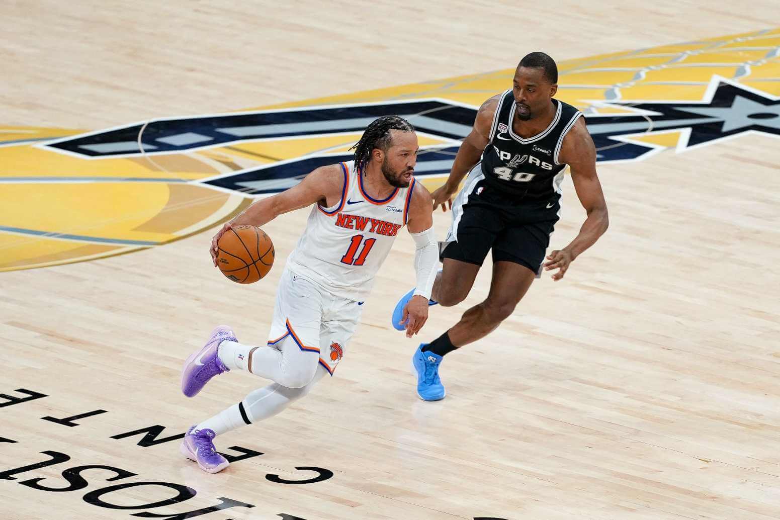 New York Knicks guard Jalen Brunson (11) looks to move the ball past San Antonio Spurs forward Harrison Barnes (40) during the fourth quarter during game one of the 2026 NBA Finals at Frost Bank Center.