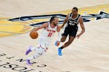 New York Knicks guard Jalen Brunson (11) looks to move the ball past San Antonio Spurs forward Harrison Barnes (40) during the fourth quarter during game one of the 2026 NBA Finals at Frost Bank Center.