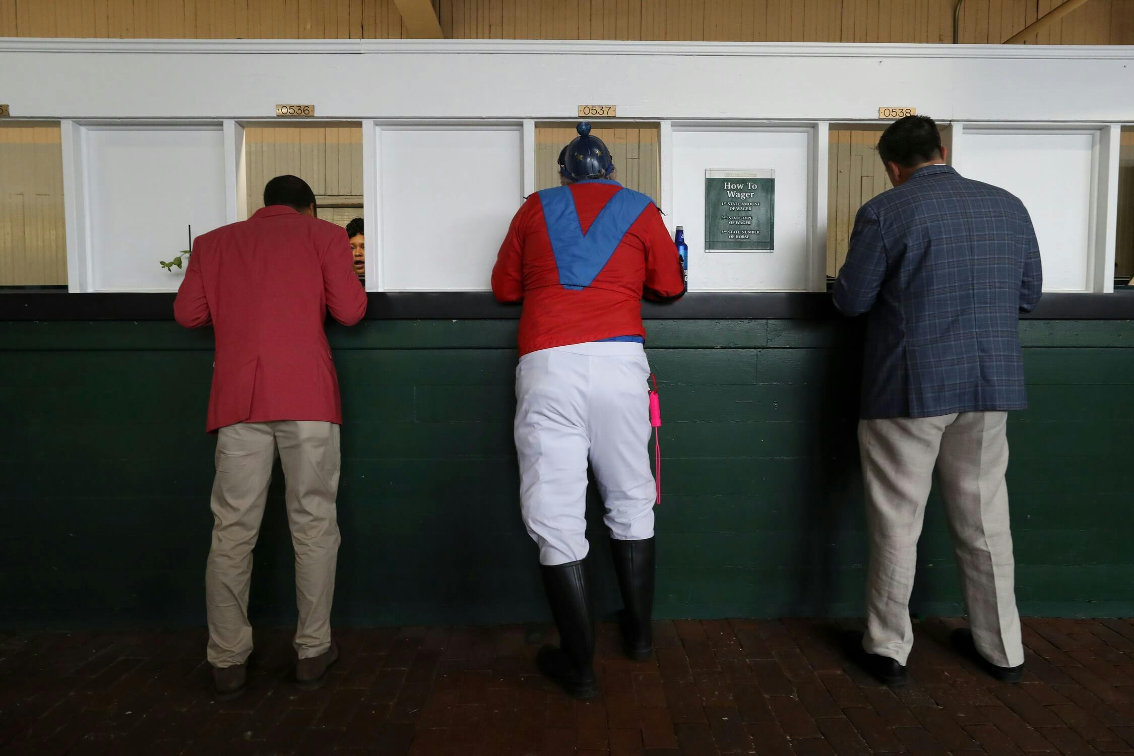 Michael Freeze, center, is not a real jockey, but that didn't stop him from dressing the part and placing a bet ahead of the Kentucky Derby at Churchill Downs on May 4, 2019