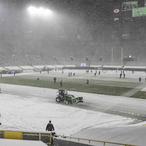 The Lambeau Field field crew in Green Bay, Wisconsin, removes snow before a game between the Green Bay Packers and Tennessee Titans on Dec. 27, 2020.