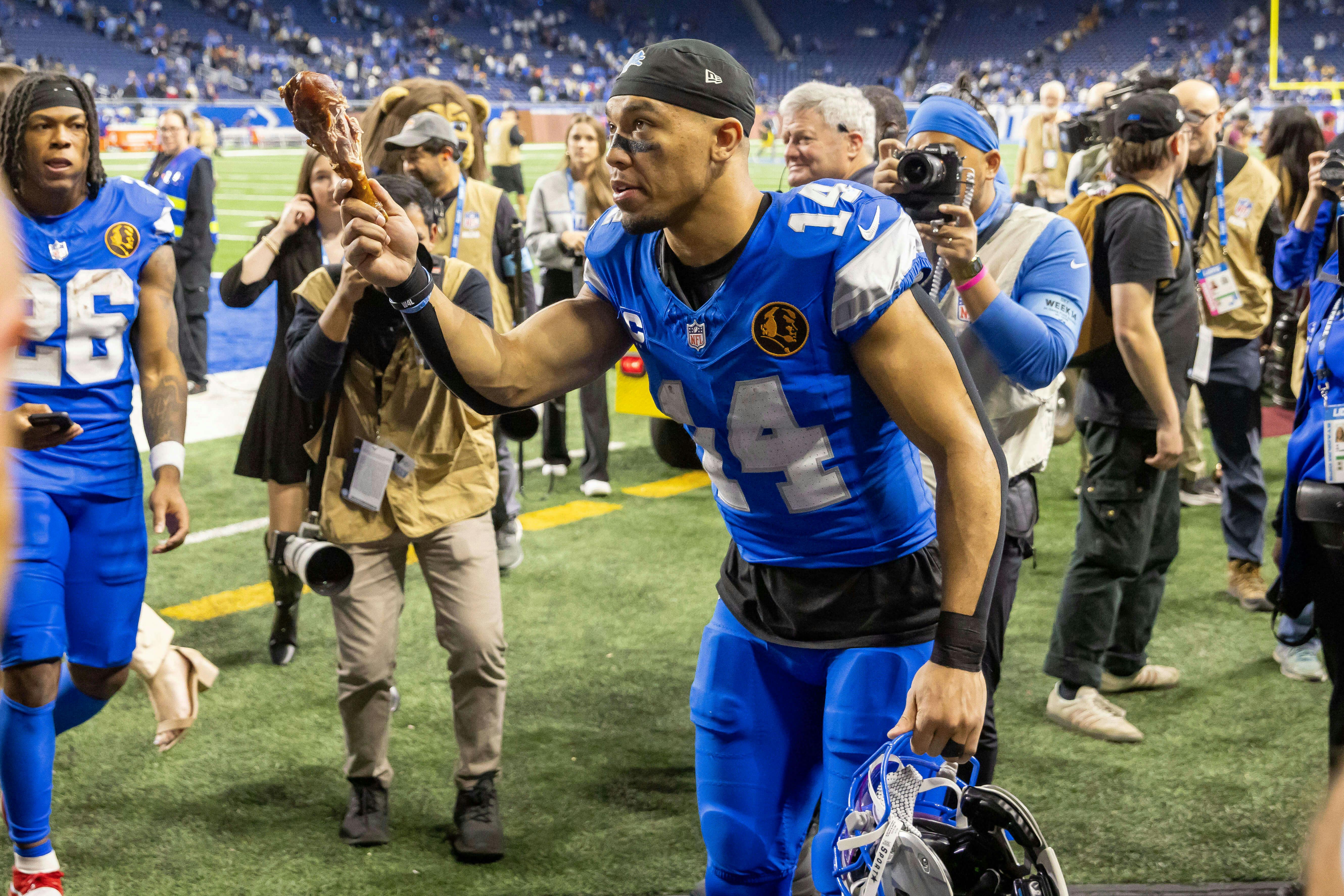 Detroit Lions wide receiver Amon-Ra St. Brown (14) tosses a turkey leg to a fan after the annual Thanksgiving Day game defeating the Chicago Bears at Ford Field. David Reginek-Imagn Images