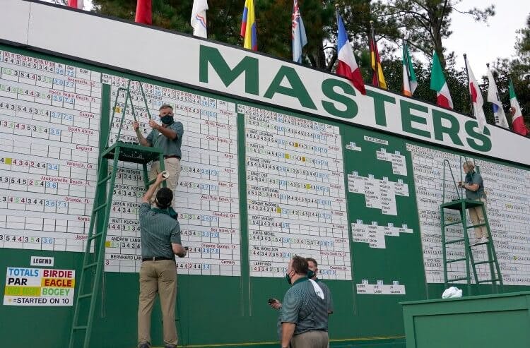 Scoreboard workers adjust the 2020 Masters leaderboard as the cut line approaches.