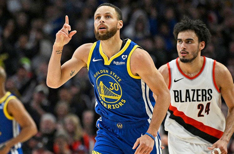 Golden State Warriors point guard Steph Curry points to the scoreboard.