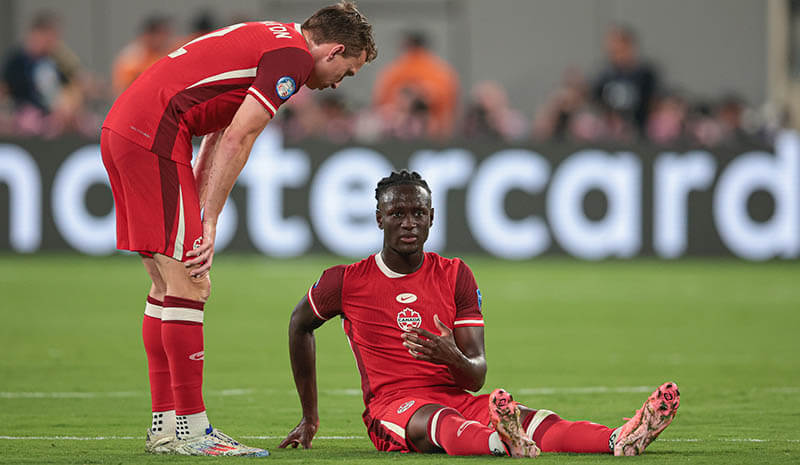 Canada midfielder Ismael Kone (8) rests on tech pitch after an injury during the second half in front of defender Alistair Johnston (2) against Argentina at Metlife Stadium.