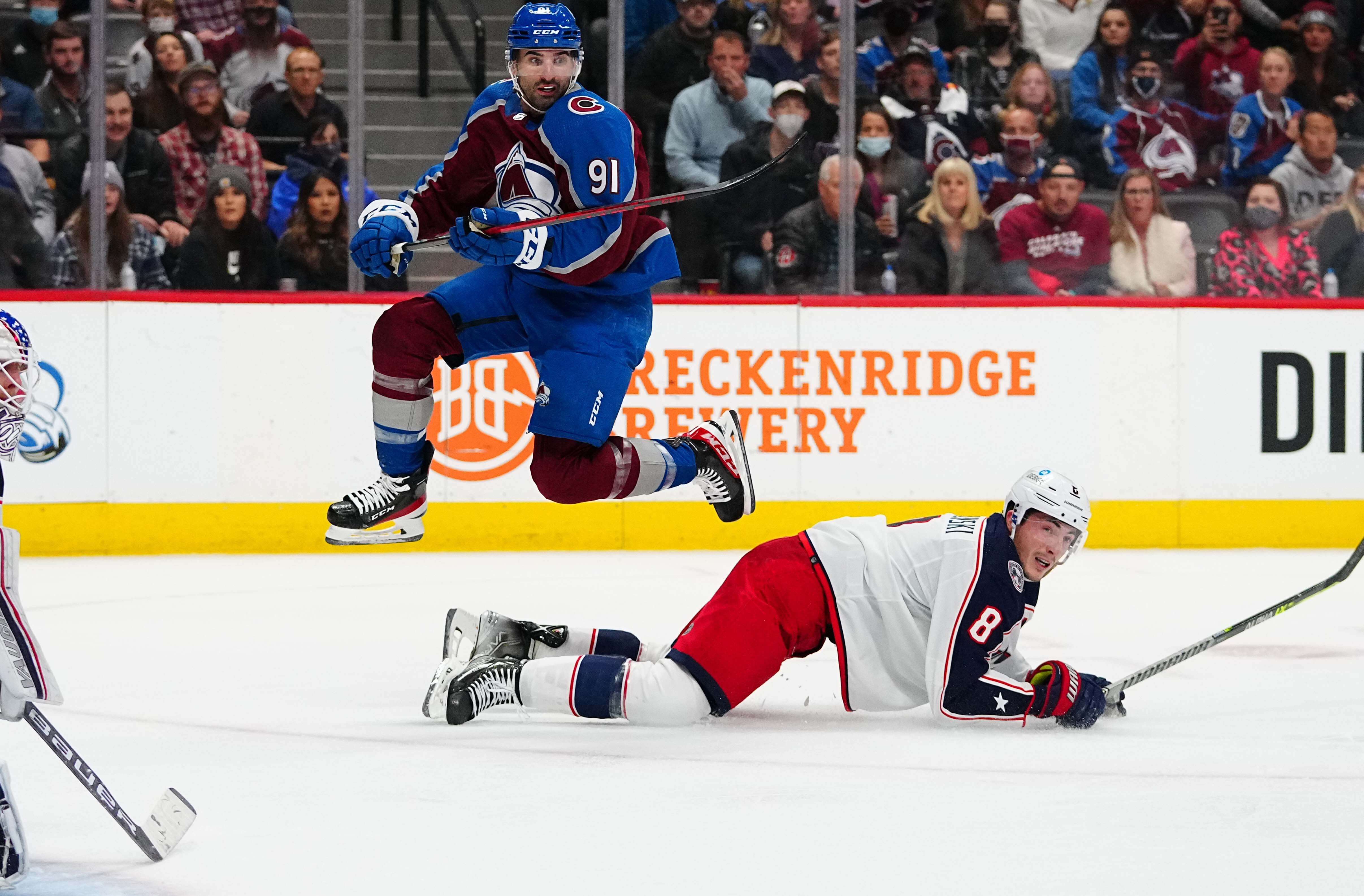 Colorado Avalanche center Nazem Kadri (91) jumps over Columbus Blue Jackets defenseman Zach Werenski (8) for an assist of a goal in the second period at Ball Arena.