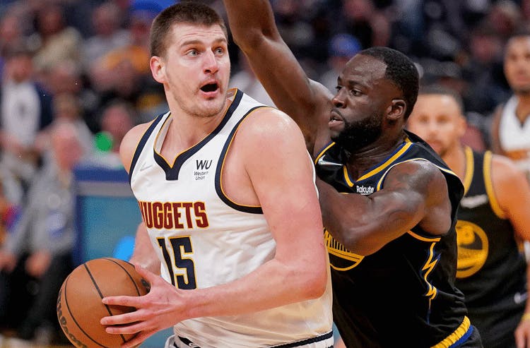 Denver Nuggets star Nikola Jokic drives to the hoop against Golden State Warriors star Draymond Green in NBA action.