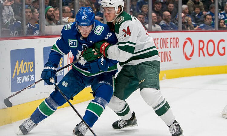 Minnesota's Joel Eriksson Ek checks Vancouver forward Bo Horvat in NHL action.