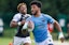 A player runs with the ball in rugby action. 